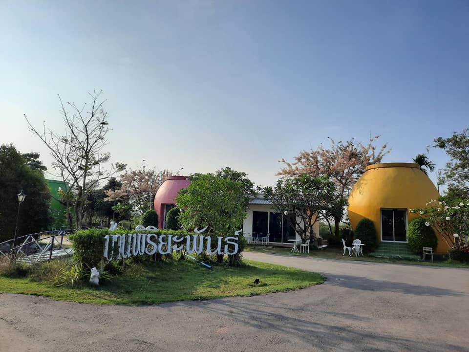 ป้ายชื่อบ้านพิริยะพันธ์ที่ทางเข้า พร้อมบ้านโอ่งสีชมพูและสีเหลืองด้านหลัง
